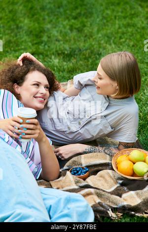 Due giovani donne condividono risate e storie mentre si gustano spuntini in una giornata di sole all'aperto. Foto Stock