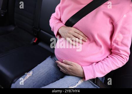 Donna incinta con cintura di sicurezza in auto, primo piano Foto Stock