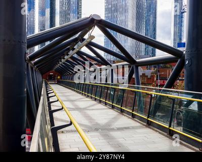 Moderno ponte pedonale con travi geometriche in acciaio in un paesaggio urbano. Stazione ferroviaria di Deansgate Manchester Regno Unito. Foto Stock