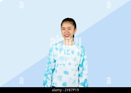 Giovane ragazza asiatica in abito blu disgusto espressione felice e gesto volto che punta Foto Stock