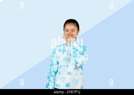 Giovane ragazza asiatica in abito blu disgusto espressione felice e gesto volto che punta Foto Stock