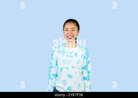 Giovane ragazza asiatica in abito blu disgusto espressione felice e gesto volto che punta Foto Stock