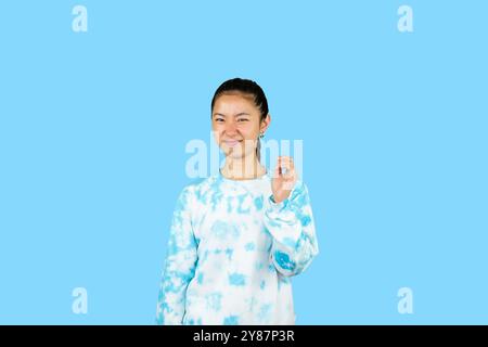 Giovane ragazza asiatica in abito blu disgusto espressione felice e gesto volto che punta Foto Stock