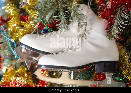 Albero di Natale adornato con pattini di ghiaccio bianchi, sport invernali e allegria natalizia, tinsel e ornamenti festivi, vigilia di Natale, sport invernali, nostalgici Foto Stock