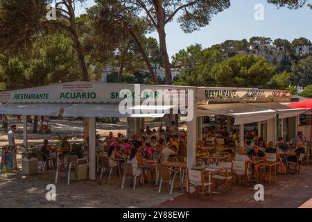 La gente gode di un ristorante sulla spiaggia della località balneare di Cala Galdana a Minorca. Foto Stock