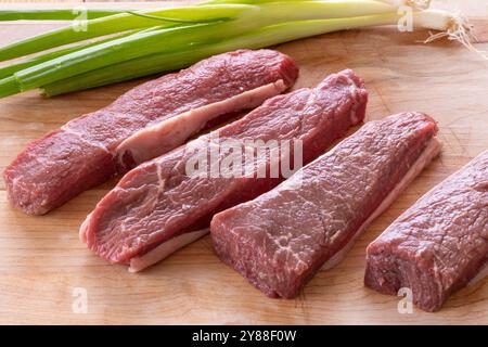 pezzi di bistecca di manzo cruda su un tagliere Foto Stock