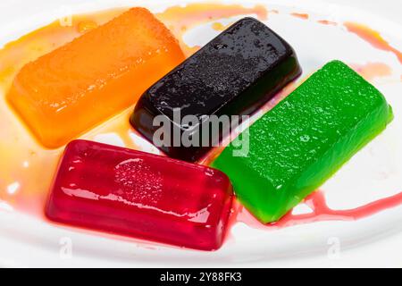 Gelatine colorate, arancione, rosso, verde, nero su piatto ovale bianco Foto Stock