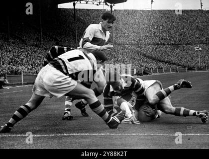 Scramble a Wembley -- Un uomo dei St. Helens si fa duro quando viene affrontato da un gruppo di giocatori degli Huddersfield. Ieri a Wembley Huddersfield ha vinto la finale di Coppa di rugby a 13 con 15 punti a 10. Oltre 90.000 persone hanno assistito a una partita veloce tra Huddersfield e St. Helens. La coppa del trofeo fu presentata a Greenall, il capitano Huddersfield, per sua grazia il duca di Norfolk. 26 aprile 1953. (Foto di Paul Popper). Foto Stock