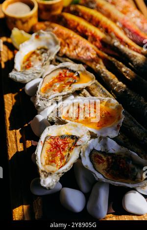 Ostriche alla griglia con salsa piccante, specialità di pesce perfette per cene raffinate, menu del ristorante Foto Stock