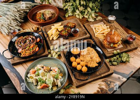 Vista dall'alto dei piatti gourmet, tra cui salsicce, costolette, schnitzel, insalata e hamburger sul tavolo Foto Stock