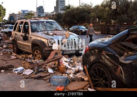 Cola, Libano. 3 ottobre 2024. Un ragazzo che indossa una giacca militare passa davanti a due auto danneggiate dai bombardamenti israeliani nel quartiere Cola alla periferia di Beirut. I continui bombardamenti in Libano hanno già sfollato più di un milione di persone e ucciso 1.400 dall'inizio della guerra tra Hezbollah e Israele. (Foto di Ximena Borrazas/SOPA Images/Sipa USA) credito: SIPA USA/Alamy Live News Foto Stock