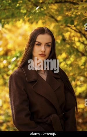 Ritratto di una giovane donna in un cappotto marrone in autunno Foto Stock