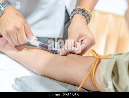 Infermiere che aspira sangue dal personale in controllo salute annuale presso l'azienda. Foto Stock