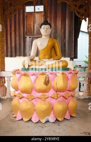 Una figura di Buddha seduta su foglie di loto rosa e oro, fiori. A Wat That Khao a Vientiane, Laos Foto Stock