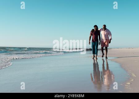 Senior afroamericano e afroamericano che si godono una passeggiata sulla spiaggia Foto Stock