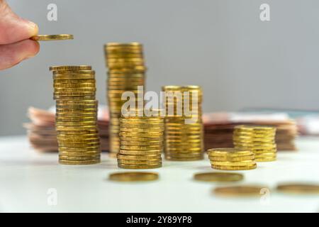 mano che tiene monete d'oro. pile di monete sul tavolo. contare i soldi accumulati. Foto Stock