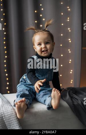 Adorabile bambina con tute in denim con acconciatura giocosa Foto Stock