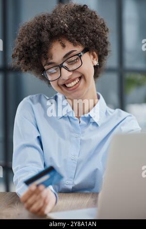 Una ragazza in un ufficio moderno paga gli acquisti su Internet utilizzando una carta di credito Foto Stock