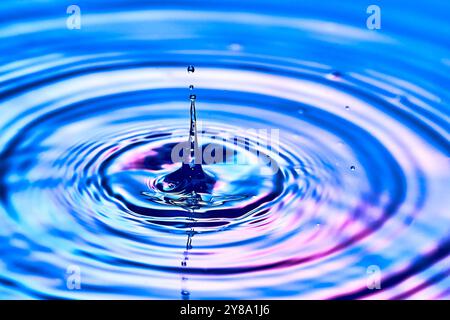 una goccia d'acqua che cade nell'acqua e crea onde Foto Stock
