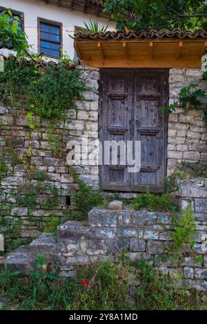 Una doppia porta in legno con gradini che vi conducono in una storica casa in pietra nel quartiere Gorica di Berat, Albania. Berat è un sito patrimonio dell'umanità dell'UNESCO Foto Stock