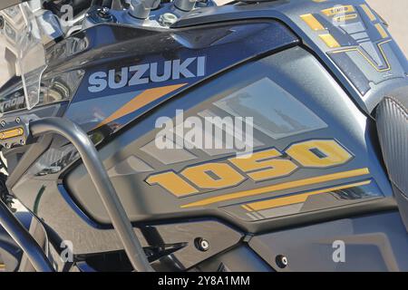 Vista ravvicinata del logo suzuki e della designazione del modello su un serbatoio del carburante per motociclette nero e giallo Foto Stock