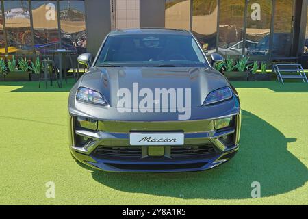 Moderno suv crossover di lusso porsche macan in piedi su erba verde di fronte ad un edificio moderno Foto Stock