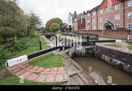 Deliziosa scena sul canale con cancelli a serratura e impugnature, pub 'Big Lock' e alloggi sul canale. Sulla Trent & Mersey a Middlewich, Cheshire, Regno Unito. Foto Stock