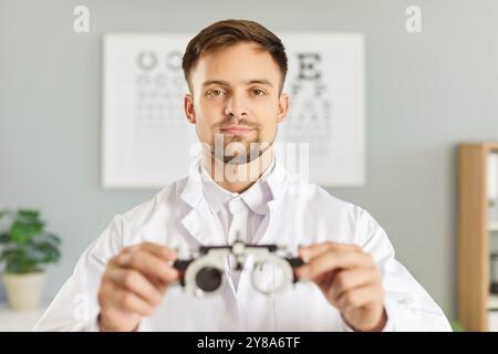 Ritratto di un giovane optometrista professionista che tiene in mano uno strumento oftalmico Foto Stock