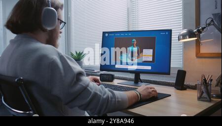 L'uomo adulto con le cuffie entra in chat con intelligenza artificiale sul personal computer. L'applicazione generatore video IA genera video dettagliati di ballerina danzante. Creazione avanzata di video generati dall'intelligenza artificiale Foto Stock