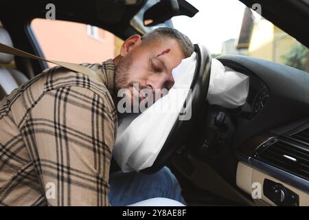 Uomo incosciente con lesioni alla testa sull'airbag in auto dopo un incidente d'auto Foto Stock