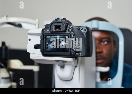 Optometrista che conduce l'esame oculare utilizzando apparecchiature diagnostiche avanzate in un ambiente clinico moderno Foto Stock