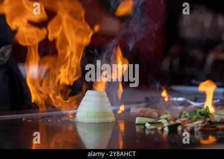 Cipolla impilata e fiamme sul teppan grill Foto Stock