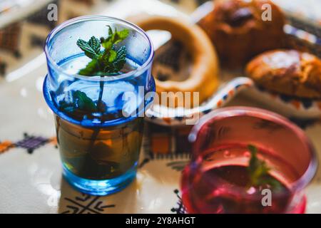 Tradizionale tè marocchino alla menta e biscotti marocchini su un tradizionale piatto di berbere su un tradizionale tappeto rosso marocchino Foto Stock