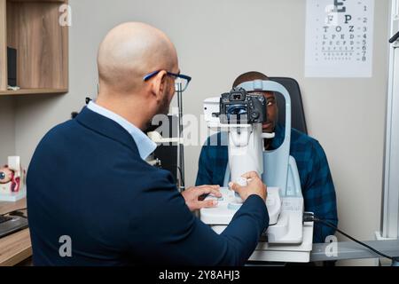 Optometrista che conduce esami di visione utilizzando apparecchiature avanzate in ambiente clinico moderno Foto Stock
