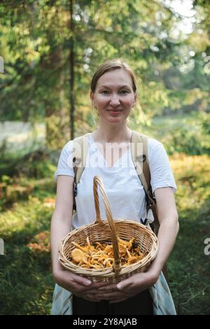 donna che raccoglie i funghi dei galletti nella foresta Foto Stock