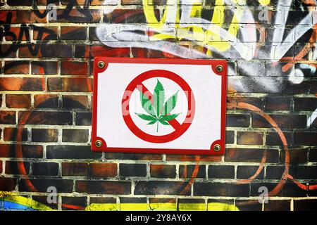 MONTAGGIO FOTOGRAFICO, cartello con una foglia di cannabis barrata su un muro, divieto di cannabis, FOTOMONTAGE, Schild mit durchgestrichenem Cannabisblatt an einer Mauer, CA Foto Stock