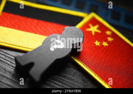 MONTAGGIO FOTOGRAFICO, figura nera con punto interrogativo sulle bandiere di Germania e Cina, foto simbolica dello spionaggio cinese, FOTOMONTAGE, Schwarze Figur mit Foto Stock