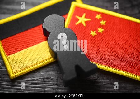 MONTAGGIO FOTOGRAFICO, figura nera con punto interrogativo sulle bandiere di Germania e Cina, foto simbolica dello spionaggio cinese, FOTOMONTAGE, Schwarze Figur mit Foto Stock