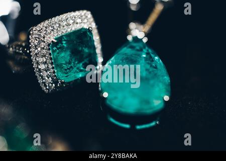 Primo piano di smeraldi nella gioielleria. Splendido anello di orecchini con pietre preziose verde smeraldo e Diamanti. Gioielli femminili di lusso, su sfondo nero Foto Stock