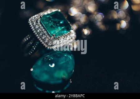 Primo piano di smeraldi nella gioielleria. Splendido anello di orecchini con pietre preziose verde smeraldo e Diamanti. Gioielli femminili di lusso, su sfondo nero Foto Stock