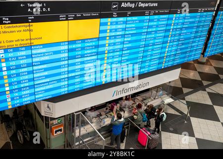 Monaco, Germania. 4 ottobre 2024. I viaggiatori si trovano sotto una bacheca presso il banco informazioni dell'aeroporto di Monaco. Un guasto tecnico al controllo del traffico aereo tedesco aveva precedentemente causato ritardi e interruzioni nello spazio aereo tedesco. Crediti: Peter Kneffel/dpa/Alamy Live News Foto Stock