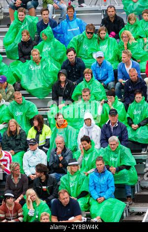 TEMPESTA ESTIVA, BEACH VOLLEY, MARIEHAMN, 2011: Fare il meglio. La folla si copre con poncho antipioggia usa e getta mentre un'enorme tempesta estiva attraversa lo stadio con un diluvio di pioggia durante le semifinali dell'agosto 2011 al PAF Open di Mariehamn, Åland, Finlandia. Fotografia: Rob Watkins. INFO: Tra il 2009-2013 il PAF Open Beach Volley è stato un torneo annuale che si è tenuto a Mariehamn, Åland, Finlandia. Ha attirato le migliori squadre e giocatori internazionali come parte della classifica ufficiale del FIVB World Tour, mostrando pallavolo da spiaggia di alto livello. Foto Stock