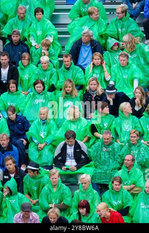 TEMPESTA ESTIVA, BEACH VOLLEY, MARIEHAMN, 2011: Fare il meglio. La folla si copre con poncho antipioggia usa e getta mentre un'enorme tempesta estiva attraversa lo stadio con un diluvio di pioggia durante le semifinali dell'agosto 2011 al PAF Open di Mariehamn, Åland, Finlandia. Fotografia: Rob Watkins. INFO: Tra il 2009-2013 il PAF Open Beach Volley è stato un torneo annuale che si è tenuto a Mariehamn, Åland, Finlandia. Ha attirato le migliori squadre e giocatori internazionali come parte della classifica ufficiale del FIVB World Tour, mostrando pallavolo da spiaggia di alto livello. Foto Stock