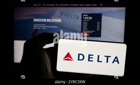 Persona che possiede uno smartphone con il logo della compagnia aerea statunitense Delta Air Lines Inc. Sullo schermo di fronte al sito Web. Mettere a fuoco il display del telefono. Foto Stock