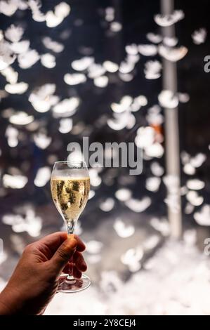 Festeggiamenti, molte piume bianche volano in aria sullo sfondo, night club con pigiama party e bicchiere di champagne spumante, ballo con vino, wedd Foto Stock