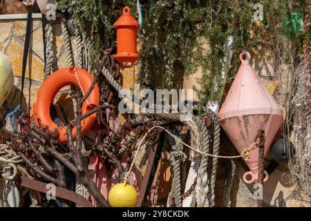 una selezione casuale di oggetti marini, marittimi e nautici, tra cui reti, galleggianti, anelli di salvataggio e corde esposti insieme davanti a una casa. Foto Stock