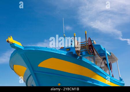 Il tradizionale peschereccio greco in legno dipinto di blu e giallo è uscito dall'acqua su un supporto rigido per una manutenzione essenziale Foto Stock