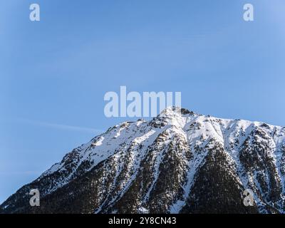 Una splendida vista sulla cima innevata del Serre Chevalier di Brianza, su un cielo azzurro e limpido. L'aspro paesaggio montano ne mette in mostra la bellezza Foto Stock