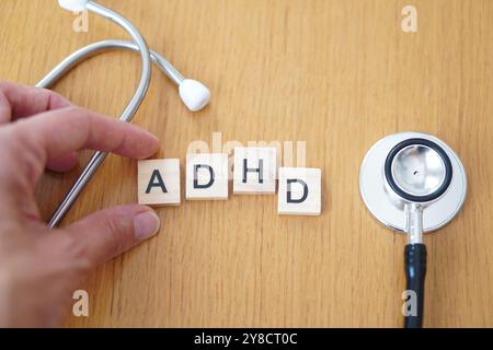 Concetto ADHD. Disturbo da deficit di attenzione e iperattività. posizionare a mano le lettere su blocchi di legno con stetoscopio. Foto Stock