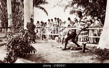 Due uomini Mikasuki Seminole tengono in mano i fucili mentre un uomo bianco combatte un alligatore al villaggio indiano di Musa Isle Seminole sul fiume Miami a Miami, Florida. (USA) Foto Stock